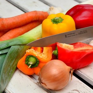 Ein Messer liegt zwischen Paprika, Lauch und Karotten